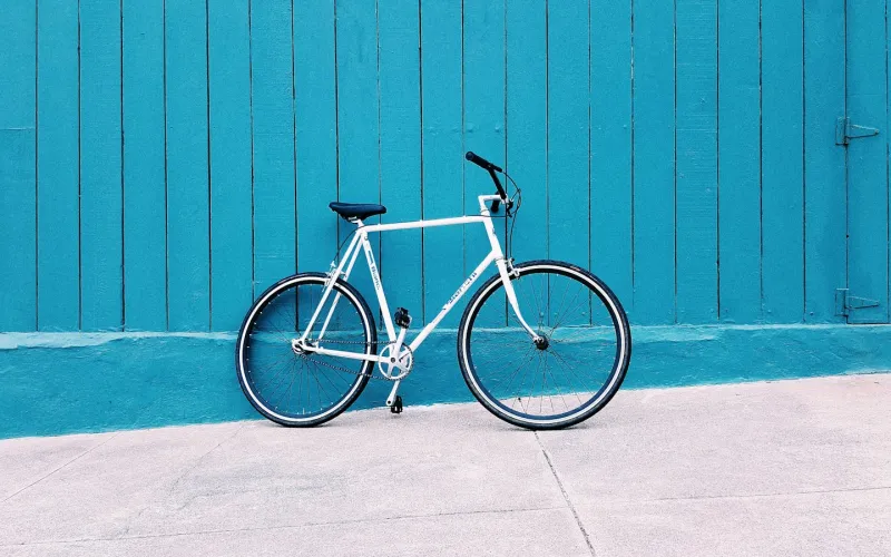 Weißes Fahrrad vor einer petrolfarbenen Holzwand